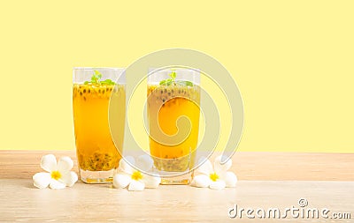 Two glass of passionfruit juice with mint and flowers on wooden table, isolated on pastel yellow background, die cut with clipping Stock Photo