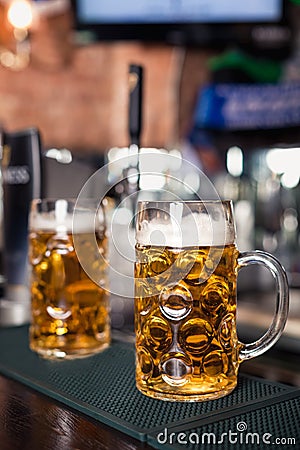 Two glasses of beer on a bar table. Beer tap on background Stock Photo