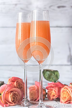 Two glasses of bellini cocktail with bouquet of roses Stock Photo