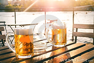 Two glasses of light beer with foam on a wooden table.On a boat. Garden party. Natural background. Alcohol. Draft beer. Landscape, Stock Photo