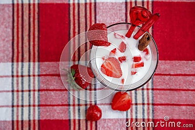 Two Glasses of Milk Cocktail,Red Fresh Strawberries with Plastic Spoons and Cinnamon on the Check Tablecloth.Breakfast Organic Stock Photo