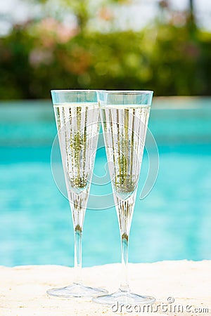 Two glasses of prosecco at the edge of a resort pool. Concept Stock Photo