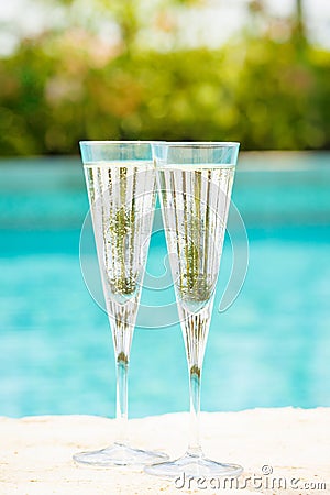 Two glasses of prosecco at the edge of a resort pool. Concept Stock Photo