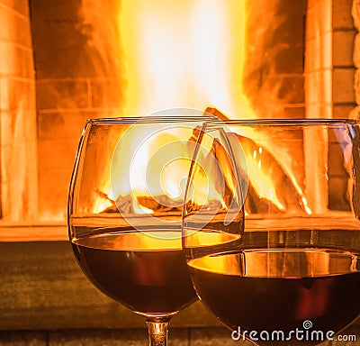 Two Glasses of red wine before fireplace. Stock Photo