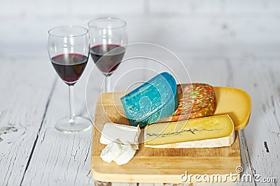 Two glasses of red wine and variation of cheese on wooden board. Stock Photo