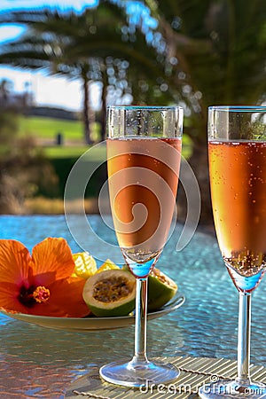 Two glasses of rose bubbles champagne or cava wine served outside on paradise island with palms and green grass Stock Photo