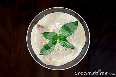 Two glasses of sweet milk dessert with coconut, peanuts and mint on black background with copy space Stock Photo