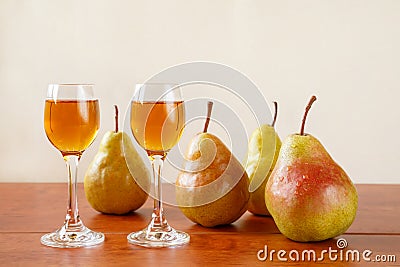 Two glasses of traditional bulgarian home made fruit brandy krushova rakia and four pears on a wooden table against light beige Stock Photo