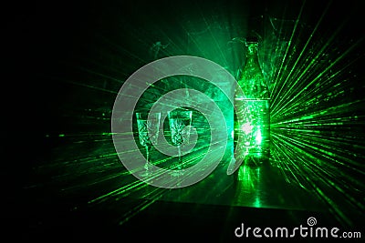 Two glasses of Vodka with bottle on dark foggy club style background with glowing lights (Laser, Stobe) Multi colored. Club drinks Stock Photo