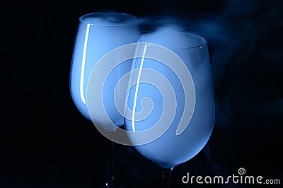 Two glasses with Vodka and martini covered with a white smoke. Stock Photo