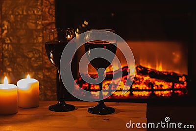 Two glasses wine with candles in front of the fireplace. Romantic atmosphere. Beautiful background with cozy magical Stock Photo