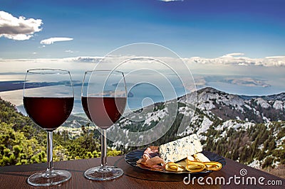 Two glasses of wine with charcuterie assortment on view of mountains and sea in Croatia. Glass of red wine with different snacks Stock Photo
