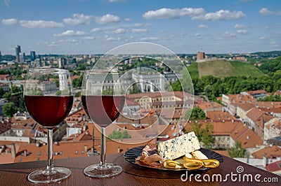 Two glasses of wine with charcuterie assortment on view of Vilnius, Lithuania. Glass of red wine with different snacks - plate Stock Photo