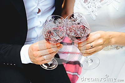 Two glasses of wine in the hands of newlyweds. Couple is clinking bocals. Stock Photo