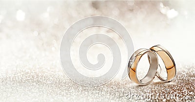 Two gold wedding bands on textured glitter Stock Photo