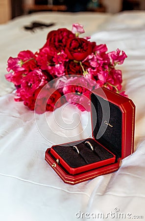21 June 2021. Two gold wedding rings Cartier on the background of a wedding bouquet, in a red box. Holiday. Pink flowers Editorial Stock Photo