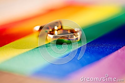 Two gold wedding rings on rainbow lgbt flag. Homosexual marriage Stock Photo