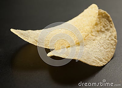 Two golden potato chips with heart shape shadow on the black Stock Photo