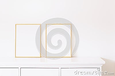 Two golden vertical frames on white furniture, luxury home decor and design for mockup creation Stock Photo