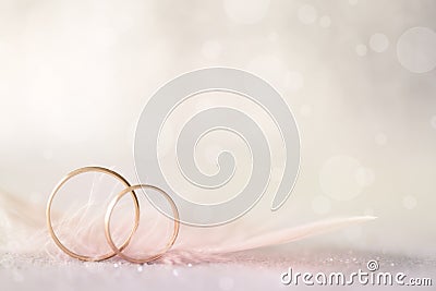 Two Golden Wedding Rings and Feather - light soft background Stock Photo