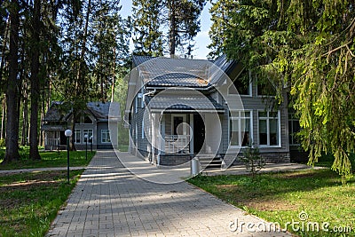 Two gray houses in a forest alley on a spring day Stock Photo