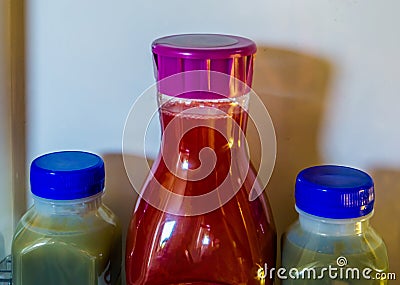 Two green and one red fruit juice in plastic bottles, healthy smoothies in the refrigerator, popular and healthy products Stock Photo