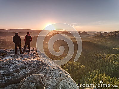 Two guys close to edge on cliff, watching awakening nature Stock Photo