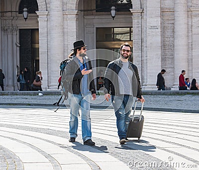 Two guys are walking through the streets of Genova, Italy and looking around, talking to each other. Stock Photo