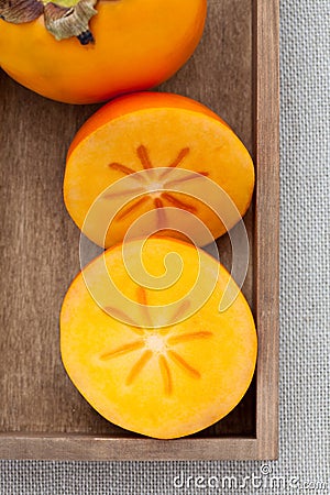 Two halves of persimmon in a wooden box Stock Photo