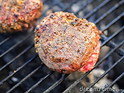 Two hamburger patties cooking on a charcoal grill Stock Photo