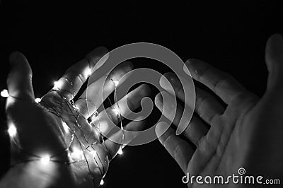 Two hands on black background one hand glowing in wire another free in dark Stock Photo