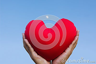 two hands gently raise and hold red heart with love and respect with background of sky Stock Photo