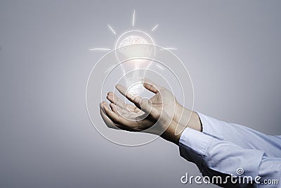 Two hands holding the drawing light bulb that is illuminating. Creative protecting patents and ideas concept Stock Photo