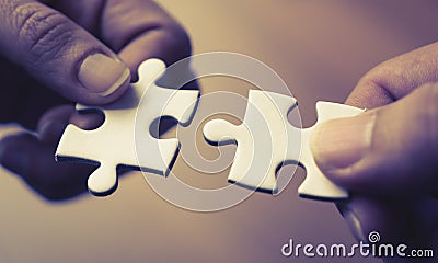 Two hands joining together two jigsaw Stock Photo