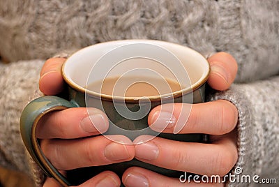 Two hands keeping warm, holding a hot cup of tea or coffee Stock Photo