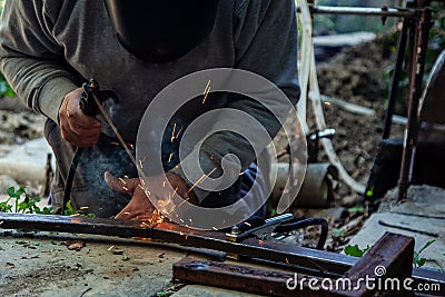 Two hands masked welder welding armature outdoors Stock Photo