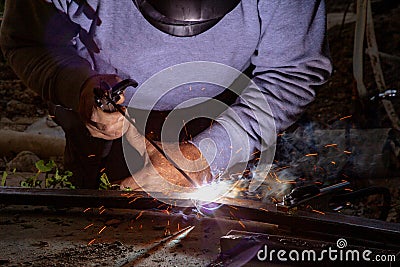 Two hands masked welder welding armature outdoors Stock Photo