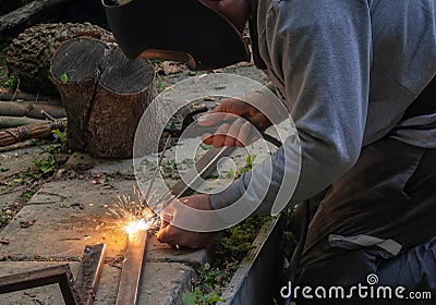 Two hands masked welder welding armature outdoors Stock Photo