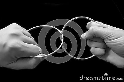 Two hands pulling rings apart that are joined together Stock Photo