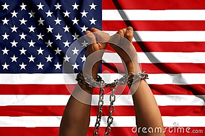 Two hands shackled a metal chain on the background of the USA flag Stock Photo