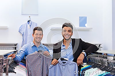 Two Handsome Business Man Fashion Shop, Happy Smiling Mix Race Friends Customers Choosing Clothes Shirts In Retail Store Stock Photo