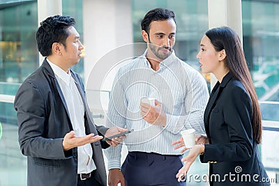 Two handsome young businessmen and lady in classic suits talking. Stock Photo