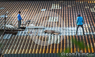 Two handyman workers repairing tiles on the damaged factory roof Editorial Stock Photo