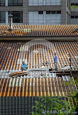 Two handyman workers repairing tiles on the damaged factory roof Editorial Stock Photo