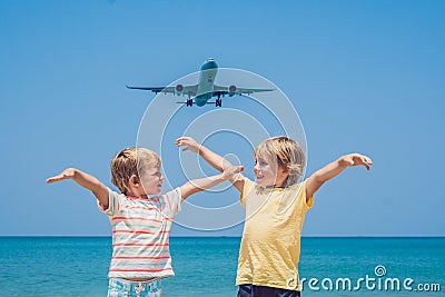 Two happy boys on the beach and a landing plane. Traveling with children concept Stock Photo