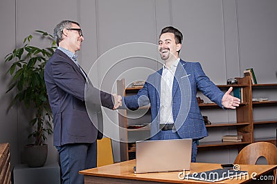 Two happy cherrful businessman in suit smiling, laughing and making handshake in office, business succes concept Stock Photo