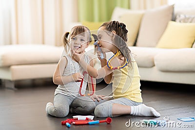 Two happy children, cute toddler girl and older sister, playing doctor and hospital using stethoscope toy and other medical toys, Stock Photo