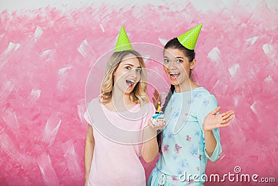 Two happy expressive girls celebrate birthday party with cupcake Stock Photo