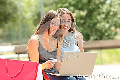 Friends shopping online paying with credit card in a park Stock Photo