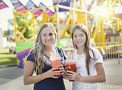 Two happy girls enjoying a cool drink at an amusement park Stock Photo